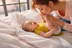 une maman qui joue avec les pieds de son bébé sur le lit